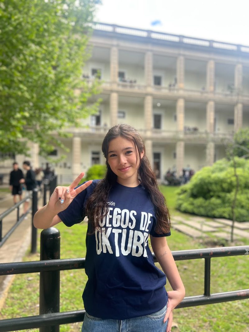 Estudiante en el patio del Nacio con la remera de Fuegos de Oktubre, vista de adelante